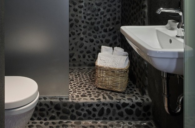 Bathroom at Thingholt apartments from Center Hotels with stone covered shower and towels in a basket.