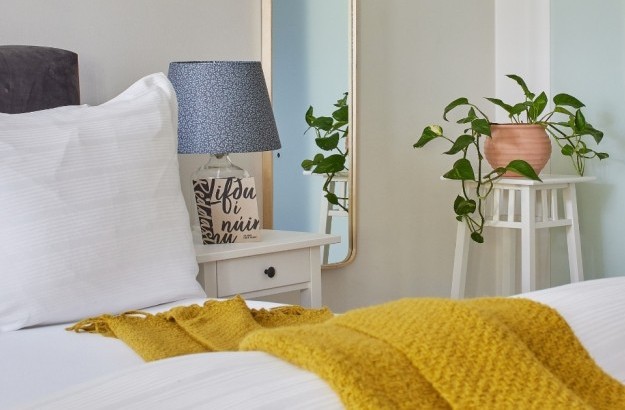 Detail of bedside table with lamp, pillow, and indoor plant in the family apartment at Thingholt apartments from Center Hotels in Reykjavik.