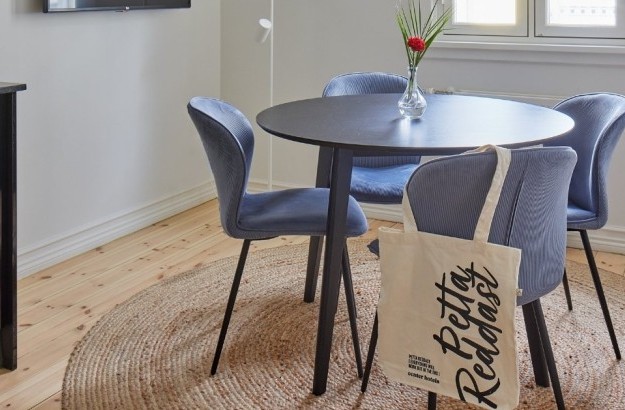 Round black table with soft blue chairs and a rug in the bright family apartment at Thingholt apartments from Center Hotels in Reykjavik.