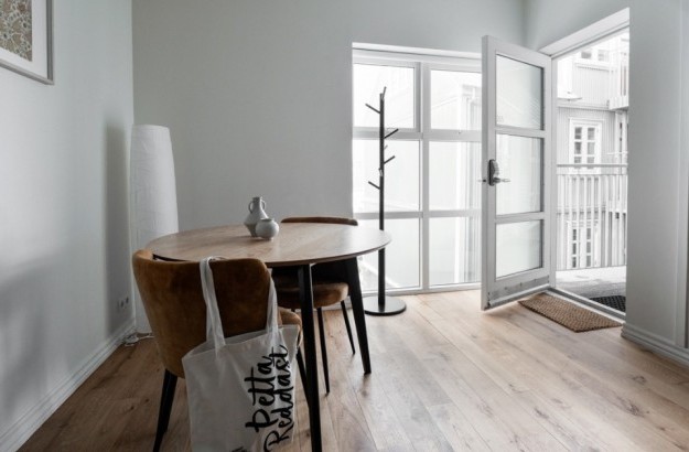 Round table with yellow chairs by a large window at Thingholt apartments from Center Hotels in Reykjavik.