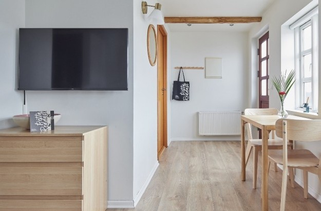 Tv area with wooden furniture and a small table near windows at Thingholt apartments from Center Hotels.