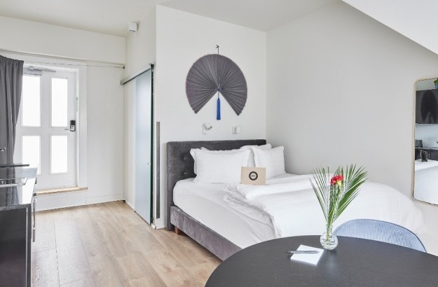 Overview of the studio apartment at Thingholt apartments from Center Hotels where there is a double bed, round table, and a black kithcenette.
