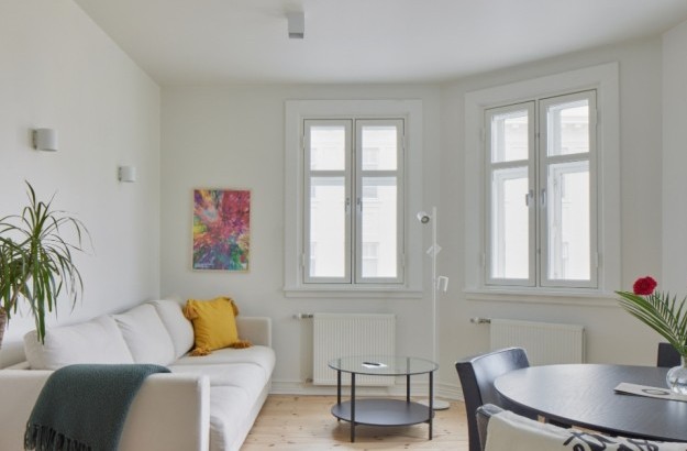 Spacious living and dining area with white sofa and large windows at Thingholt apartments from Center Hotels in Reykjavik.
