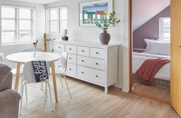 Cosy two bedroom apartment at Thingholt Apartments with large windows, round table, and white chest of drawers.