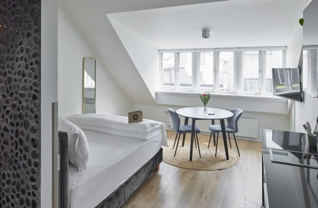 Spacious studio apartment with bed, round dining table, and large window at Thingholt Apartments by Center Hotels in Reykjavik.