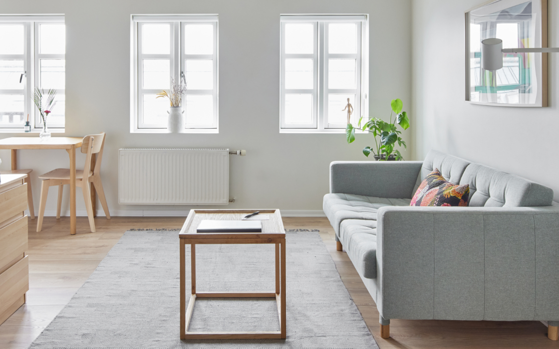 Modern living room with light wood furniture and soft grey sofa at Thingholt apartments by Center Hotels in Reykjavik.
