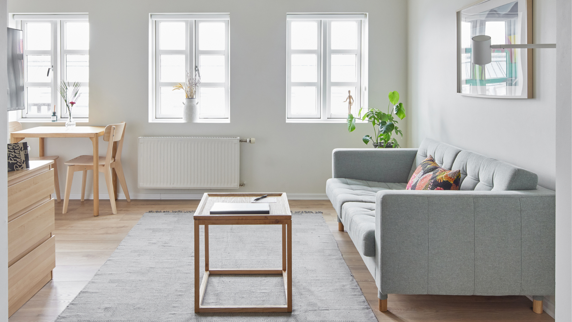 Modern living room with light wood furniture and soft grey sofa at Thingholt apartments by Center Hotels in Reykjavik.