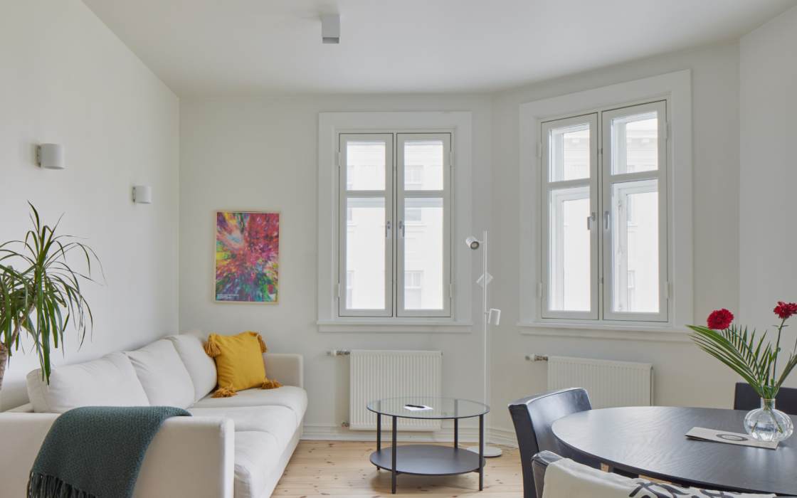 Spacious living and dining area with white sofa and large windows at Thingholt apartments from Center Hotels in Reykjavik.