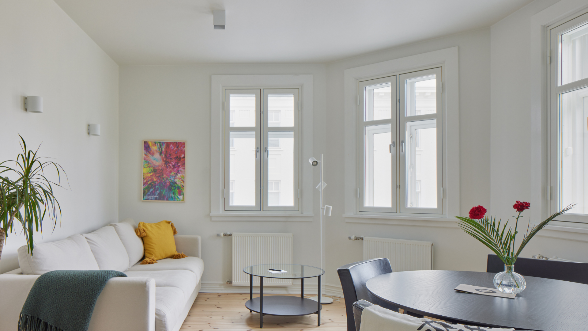 Spacious living and dining area with white sofa and large windows at Thingholt apartments from Center Hotels in Reykjavik.