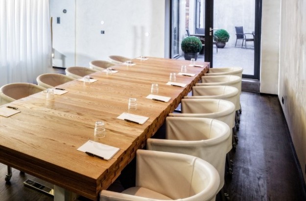 isafold Meeting Room at Thingholt by Center Hotels in Reykjavík featuring a long natural wood conference table, modern cream chairs on casters, notepads and glasses arranged for a meeting, wi