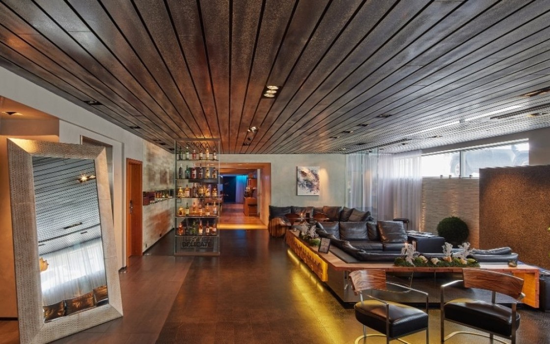 Lobby lounge at Thingholt by Center Hotels showing a tall decorative mirror, cozy lounge area with leather sofas, designer lighting, bar shelves with spirits, and natural daylight filtering