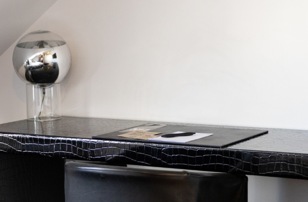 A black desk with a chrome lamp in a standard room at Thingholt by Center Hotels.