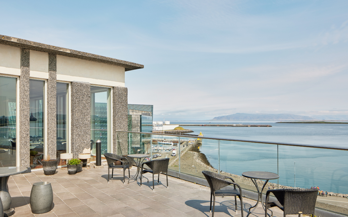 The view from the balcony at the rooftop bar Sky at Center Hotels Arnarhvoll in Reykjavik overlooking the ocean, mountains and Harpa Concert Hall.