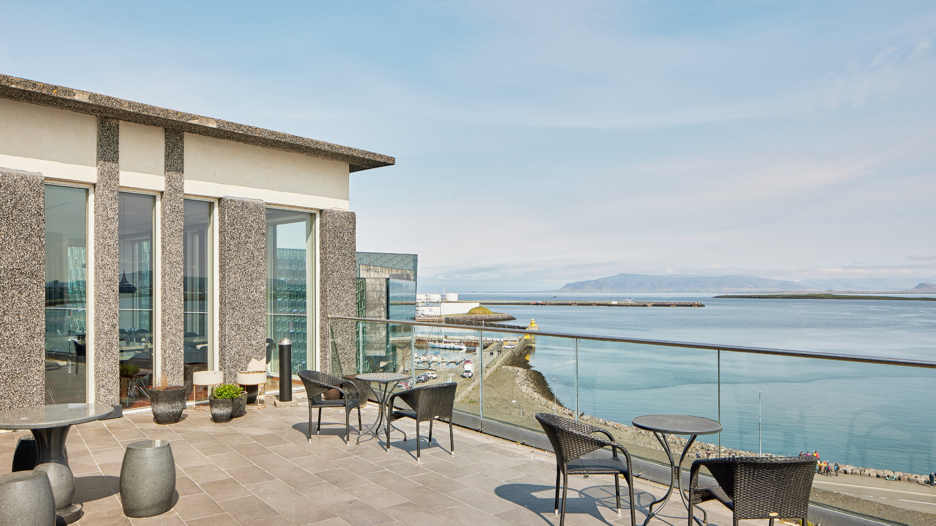 The view from the balcony at the rooftop bar Sky at Center Hotels Arnarhvoll in Reykjavik overlooking the ocean, mountains and Harpa Concert Hall.