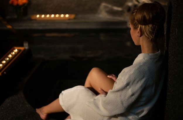 A woman relaxing in a white bathrobe by the hot tub in the wellness area at Center Hotels Arnarhvoll in Reykjavik.