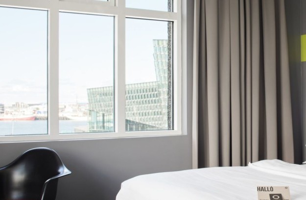 Rúm í deluxe herbergi á Center Hotels Arnarhvoli í Reykjavík með útsýni yfir Hörpu tónlistarhús.