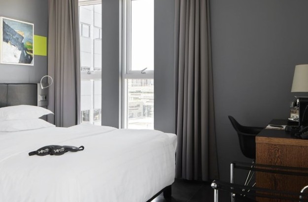 Deluxe herbergi með sjávarútsýni á Center Hotels Arnarhvoll í Reykjavik, með þægilegu hjónarúmi, veggskreytingu og skrifborði við gólfsíða glugga með útsýni yfir borgina.