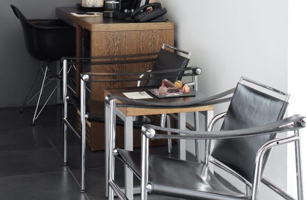 Seating area in the Sea View Deluxe Room at Center Hotels Arnarhvoll in Reykjavik, featuring sleek leather chairs and a welcome note with treats.