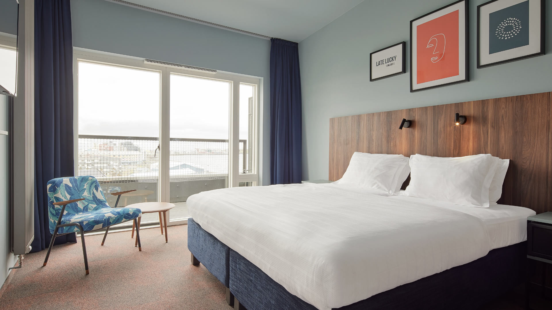 Balcony room at Grandi by Center Hotels in Reykjavik with kind bed, wall art, and large window doors opening to private balcony.
