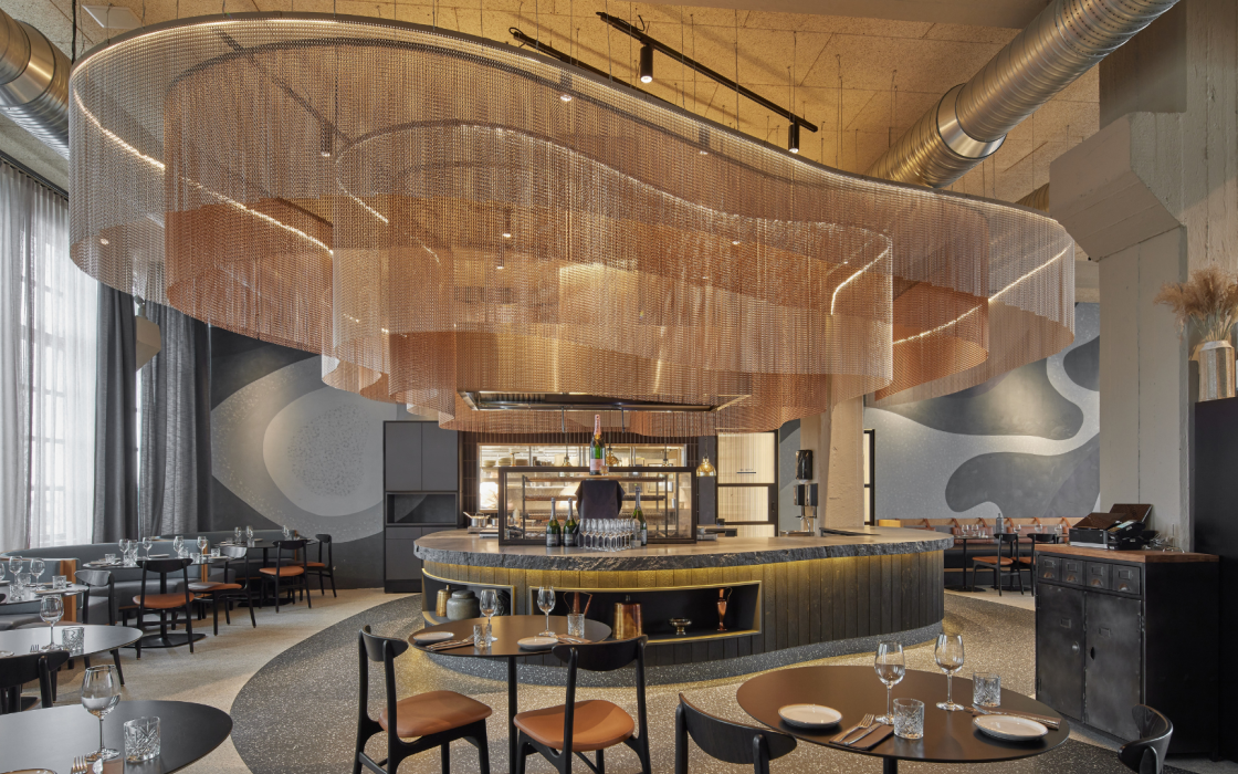 Modern designed restaurant at Grandi by Center Hotels in Reykjavik, Iceland, with sculptural copper ceiling installation and round tables.