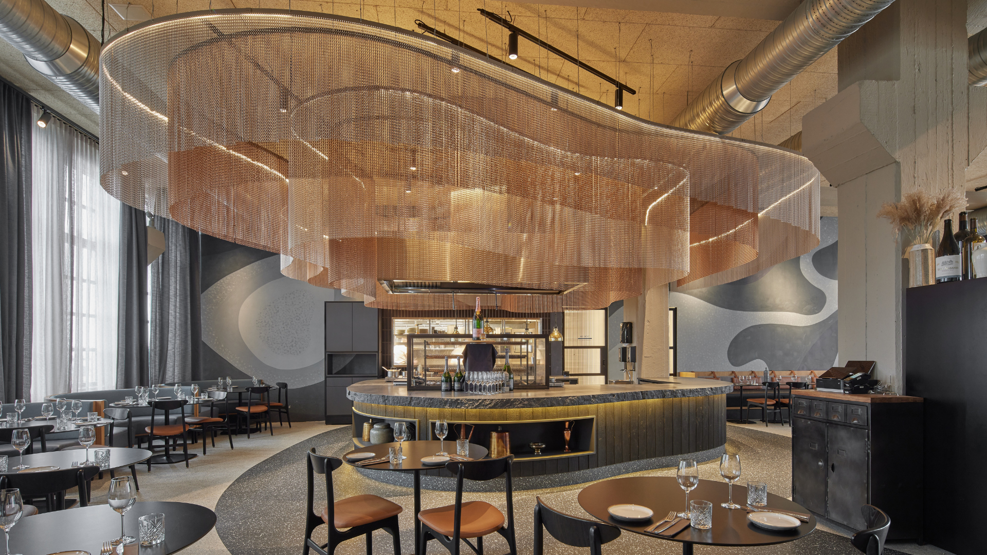 Modern designed restaurant at Grandi by Center Hotels in Reykjavik, Iceland, with sculptural copper ceiling installation and round tables.
