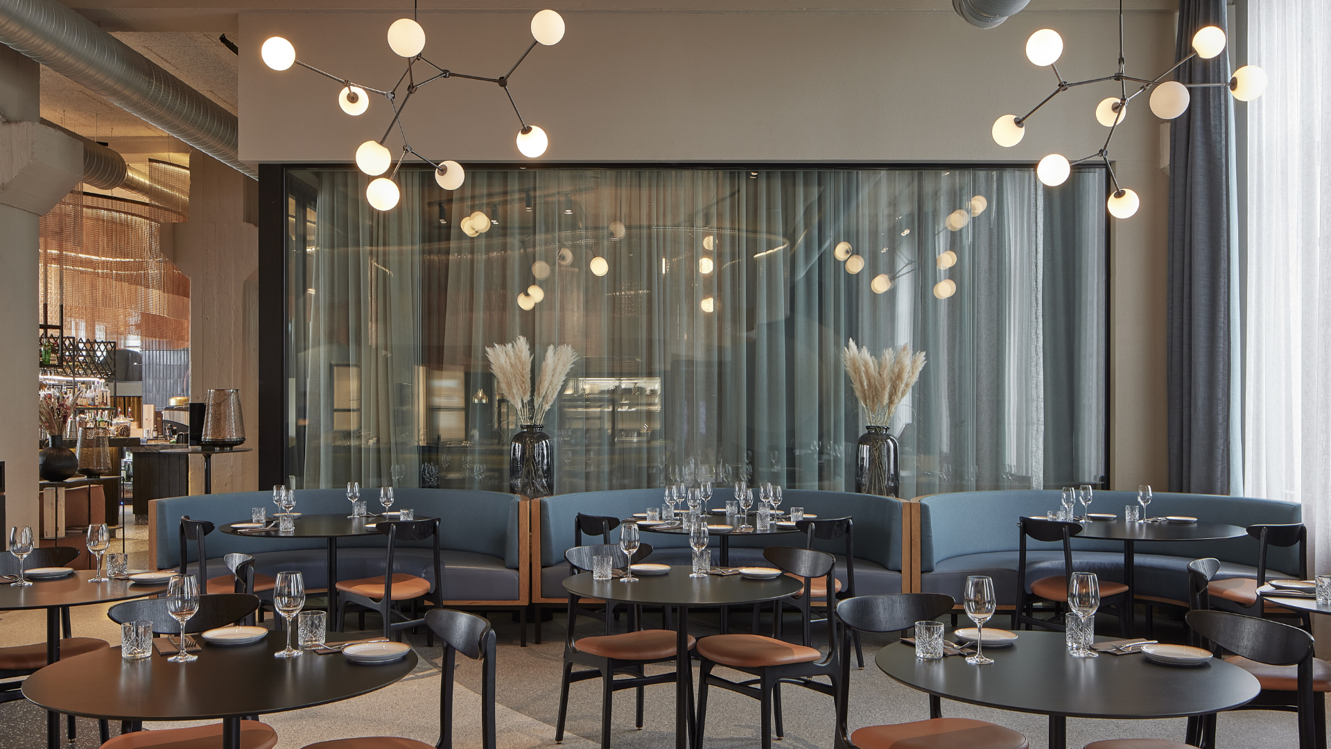 Contemporary restaurant at Grandi by Center Hotels in Reykjavik featuring curved booth seating, minimalist table settings, and striking ceiling lights.