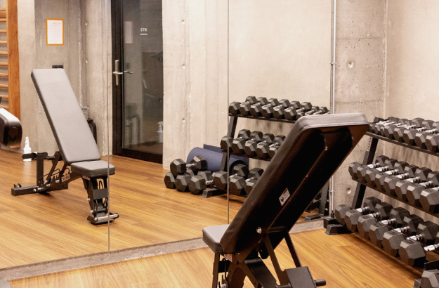 A picture of the gym at Grandi by Center Hotels showing weights, bench and a treadmill