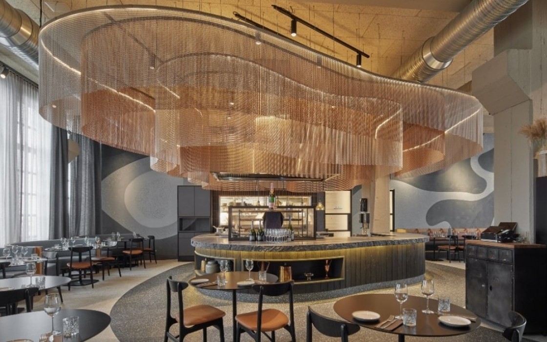 Modern designed restaurant at Grandi by Center Hotels in Reykjavik, Iceland, with sculptural copper ceiling installation and round tables.