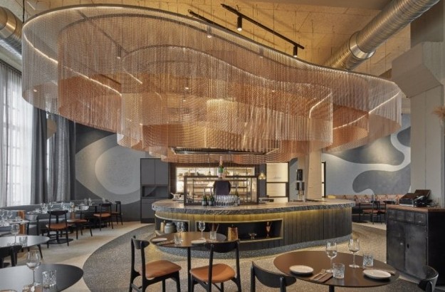  Modern designed restaurant at Grandi by Center Hotels in Reykjavik, Iceland, with sculptural copper ceiling installation and round tables.