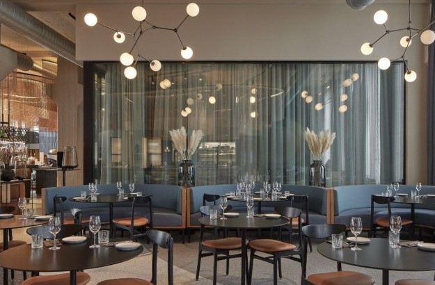 Contemporary restaurant at Grandi by Center Hotels in Reykjavik featuring curved booth seating, minimalist table settings, and striking ceiling lights.