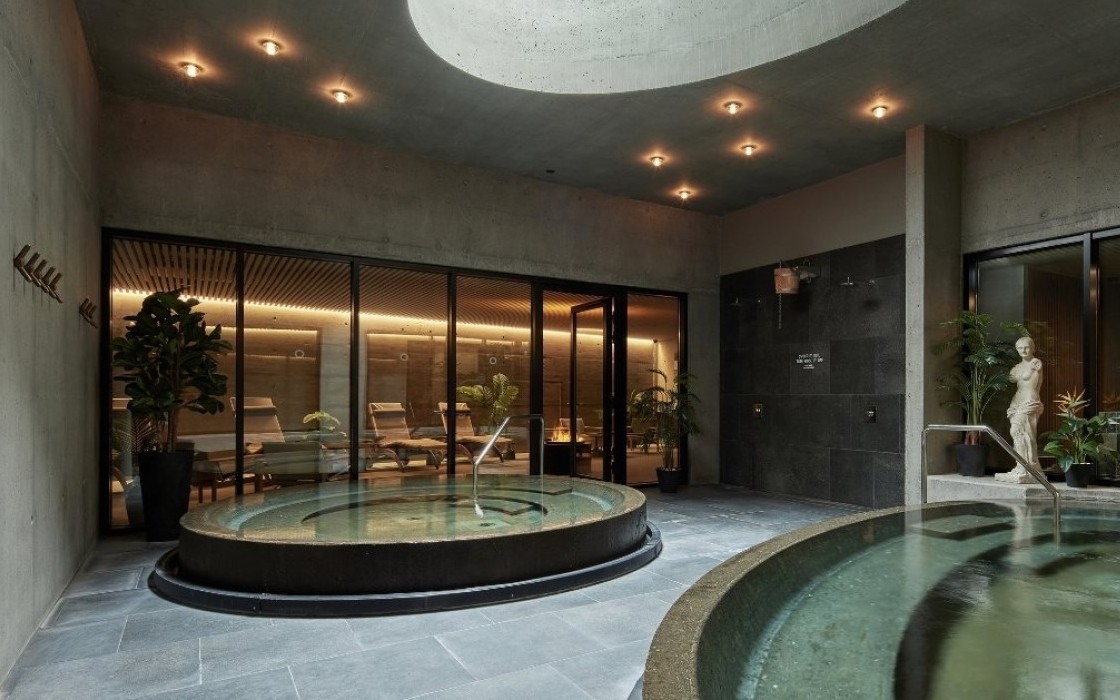  Indoor spa area at Grandi by Center Hotels in Reykjavik with round hot tubs, lounge chairs and natural concrete walls.