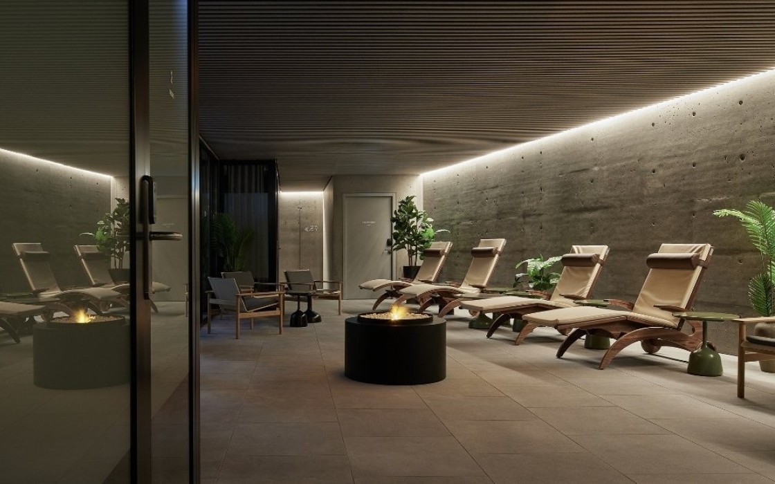 Tranquil spa lounge at Grandi by Center Hotels in Reykjavik, with reclining loungers, plants, and a central firepit.