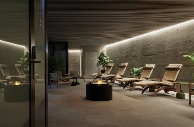 Tranquil spa lounge at Grandi by Center Hotels in Reykjavik, with reclining loungers, plants, and a central firepit.