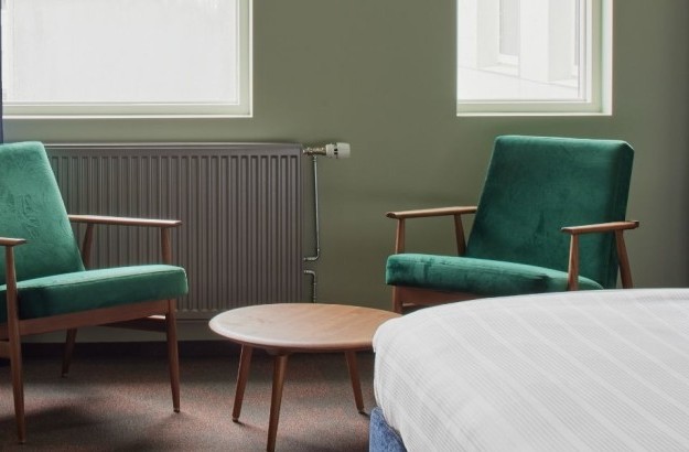 Pair of green velvet lounge chairs with round table in the deluxe kind room at Grandi by Center Hotels in Reykjavik.