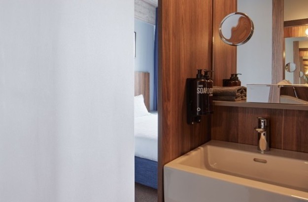 Bathroom area of the junior suite at Grandi by Center Hotels in Reykjavik with a view into bedroom, bathtub, and modern sink design.