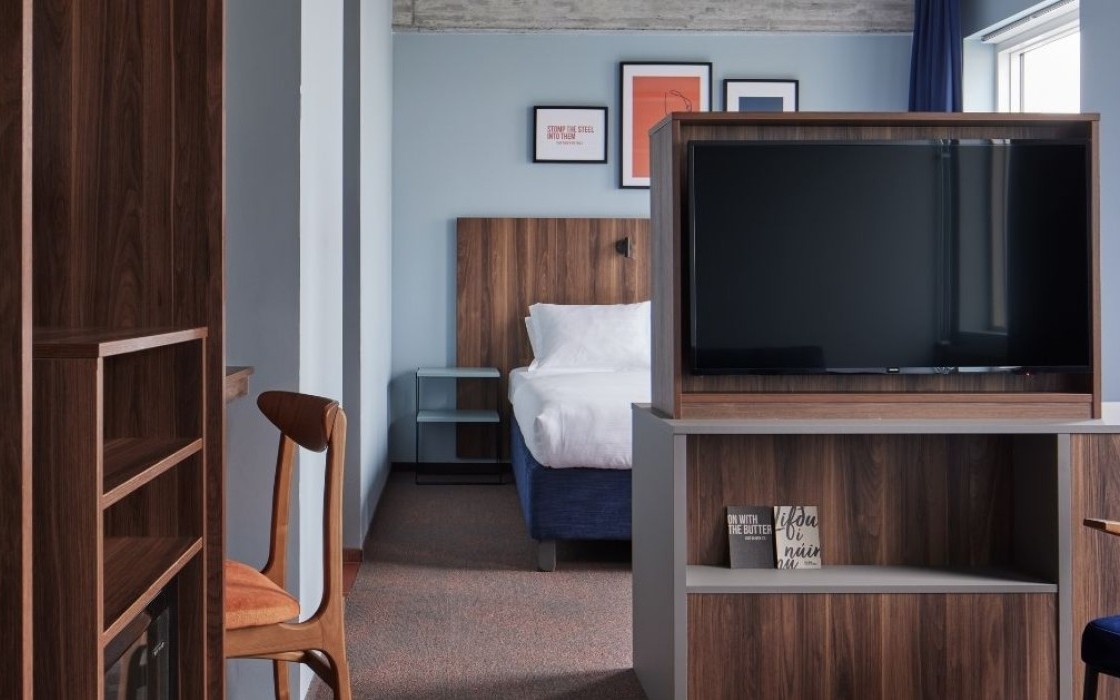 Junior suite at Grandi by Center Hotels in Reykjavik showing the bed behind a wooden TV partition and desk area.