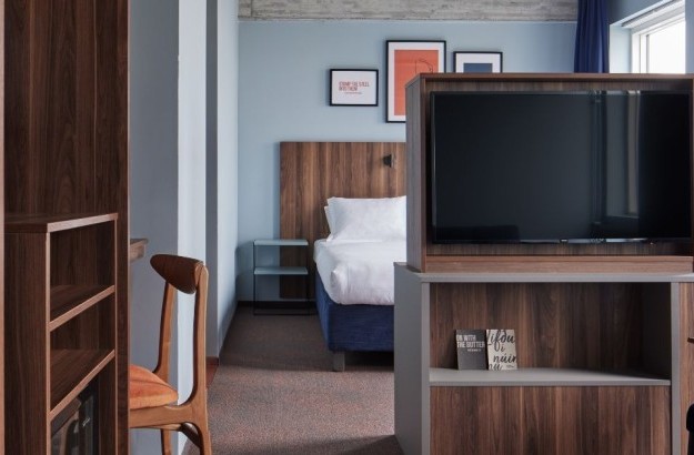 Junior suite at Grandi by Center Hotels in Reykjavik showing the bed behind a wooden TV partition and desk area.
