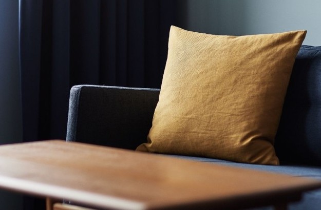 Detail of dark blue sofa with yellow cushion in the junior suite at Grandi by Center Hotels in Reykjavik.