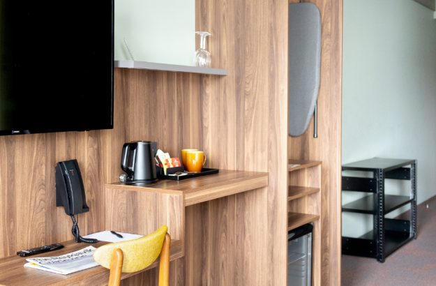 Close up of the desk area in a standard plus room at Grandi by Center Hotels with a yellow chair and wooden desk.