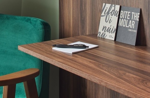 Desk and green chair in the standard double/twin room at Grandi by Center Hotels with wooden finishes and artistic postcards.