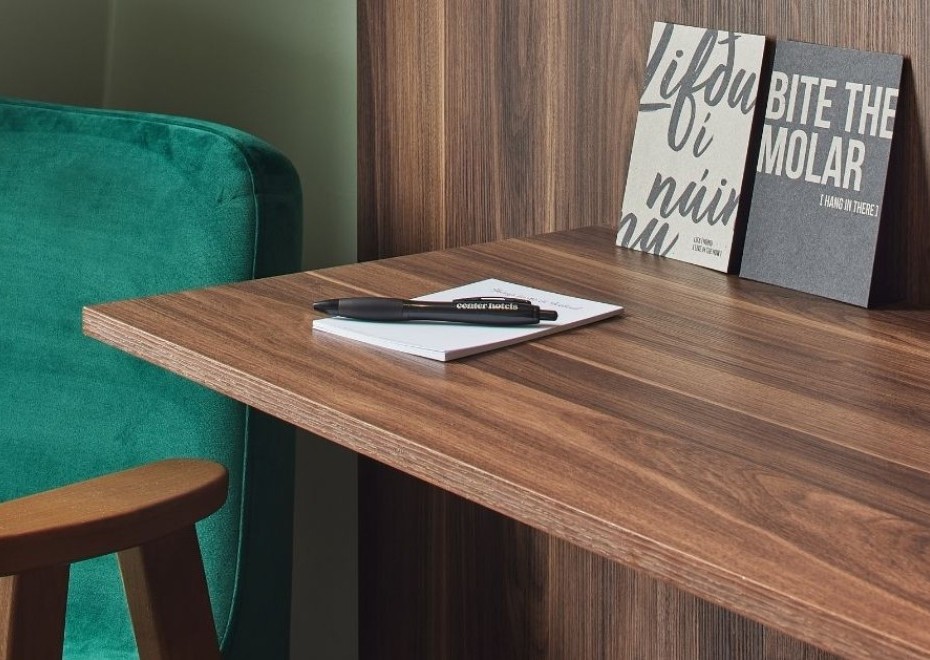 Desk and green chair in the standard double/twin room at Grandi by Center Hotels with wooden finishes and artistic postcards.