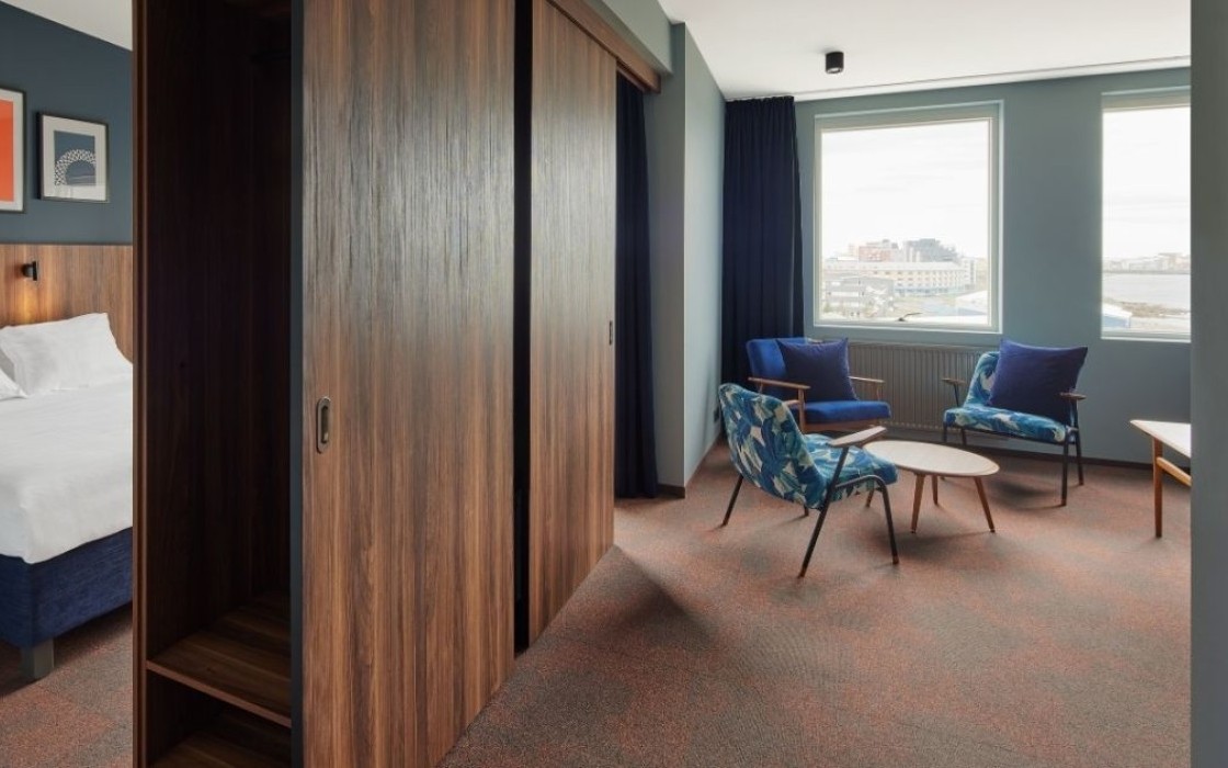 Open-plan suite at Grandi by Center Hotels in Reykjavik showing the bedroom and separate lounge with patterned armchairs.
