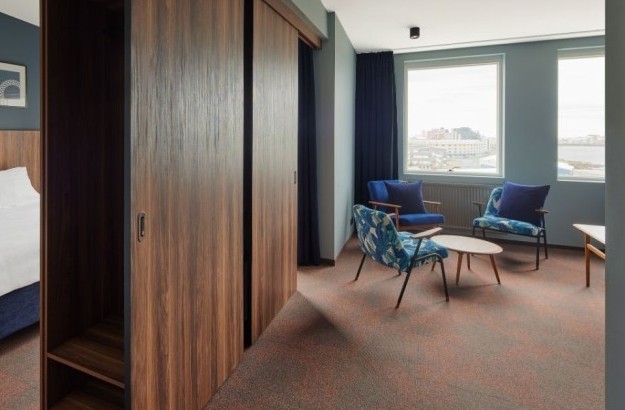 Open-plan suite at Grandi by Center Hotels in Reykjavik showing the bedroom and separate lounge with patterned armchairs.