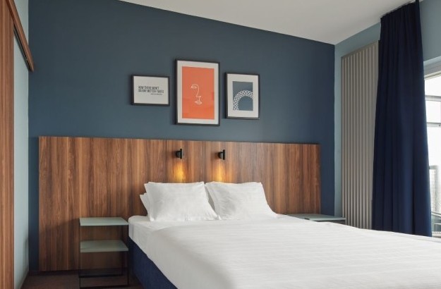 Suite bedroom at Grandi by Center Hotels in Reykjavik with navy blue wall, framed artwork, and wooden headboard.