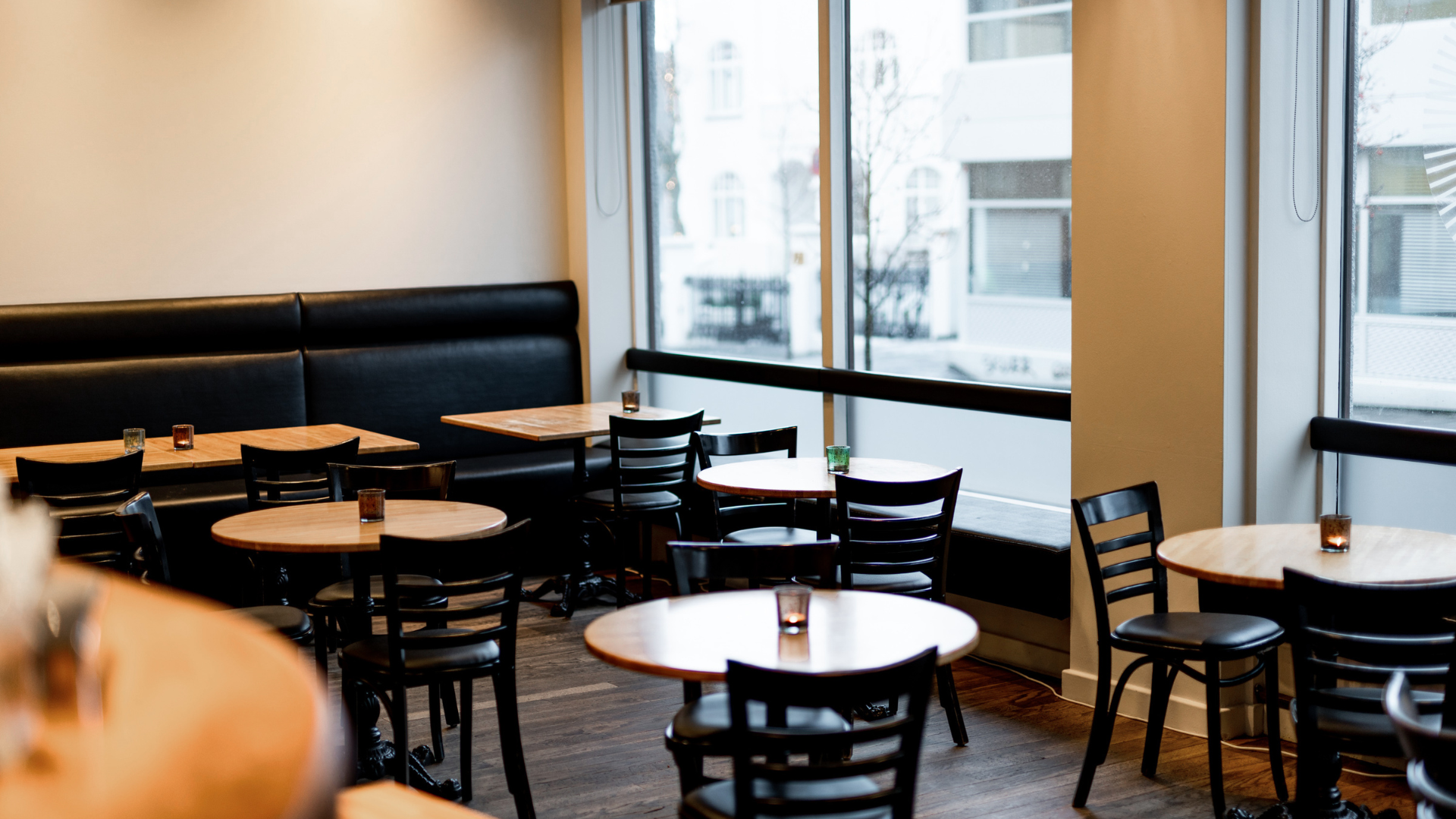 The breakfast area at Center Hotels Klopp in Reykjavik with big windows, round tables and black chairs.