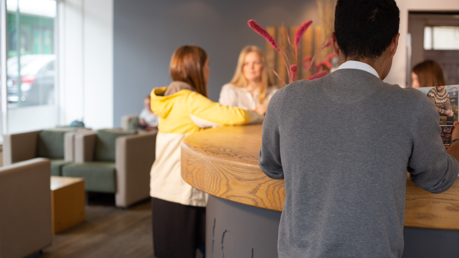 Guests being welcomed at the front desk of Center Hotels Klopp in Reykjavik, with wooden reception counter, comfortable lounge chairs, and warm lighting.