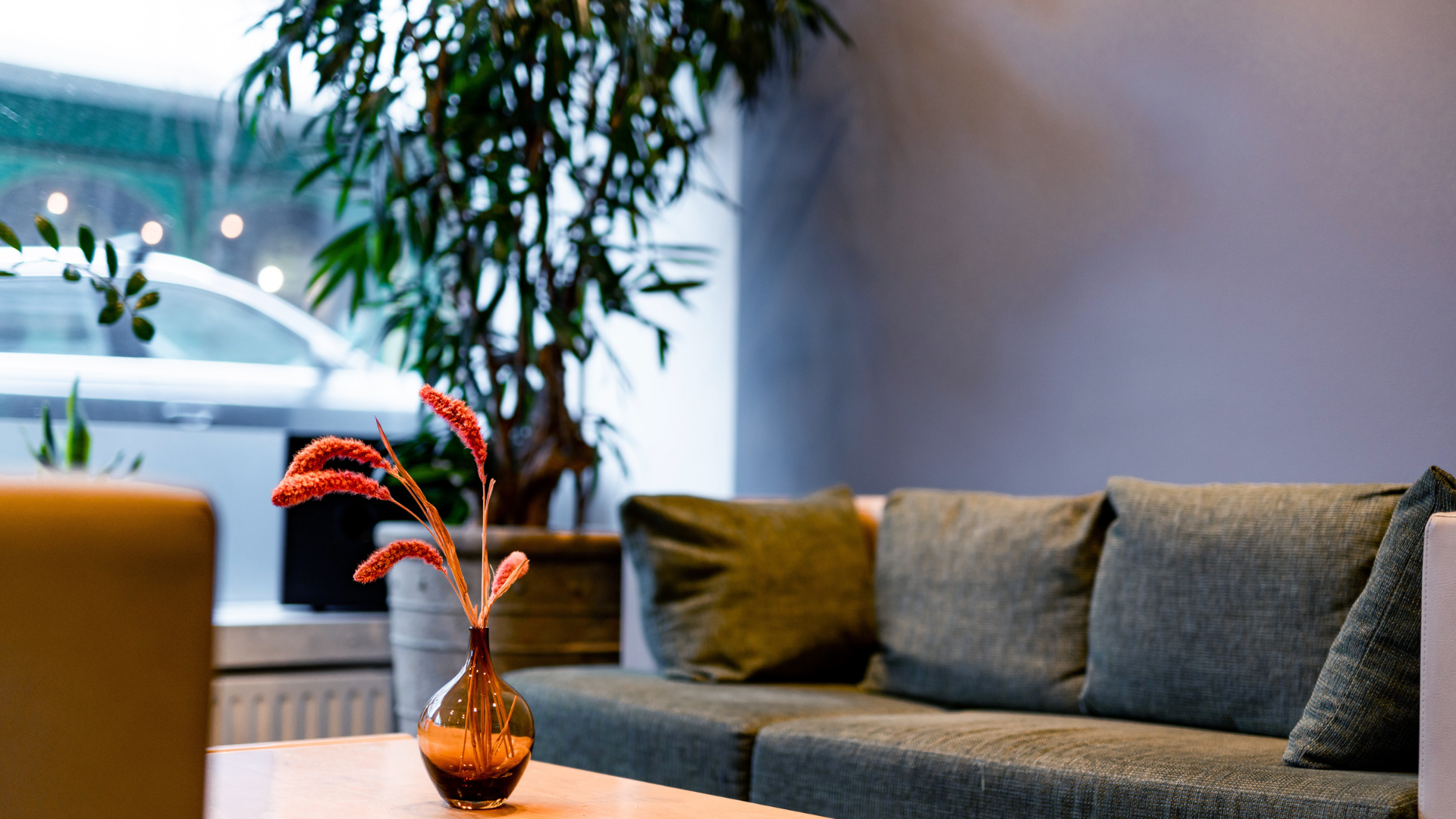  Lobby lounge at Center Hotels Klopp in Reykjavik, featuring a green fabric sofa, indoor plant, and decorative vase on a wooden coffee table.