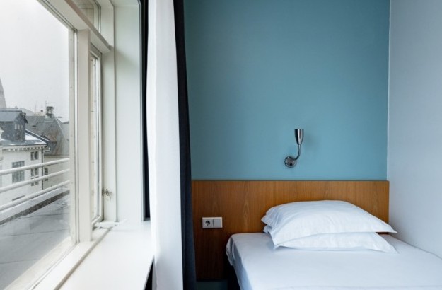 City view from a standard single room at Center Hotels Klopp in Reykjavik, with the Hallgrimskirkja church visible through the large window beside the bed.