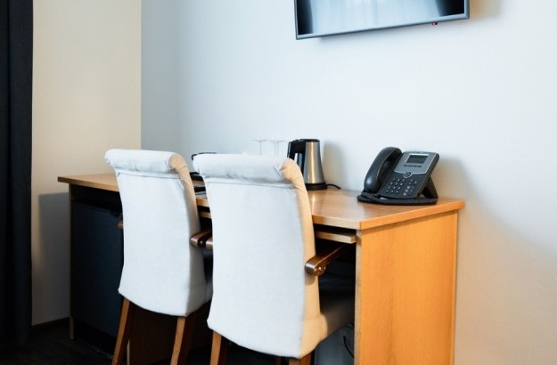 Desk area in a superior room at Center Hotels Klopp in Reykjavik with two white chairs, kettle, glassware, and mounted flat-screen TV.