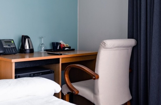 Close-up of the work desk and amenities in a superior single room at Center Hotels Klopp in Reykjavik, including a phone, electric kettle, glasses, and tea/coffee setup.